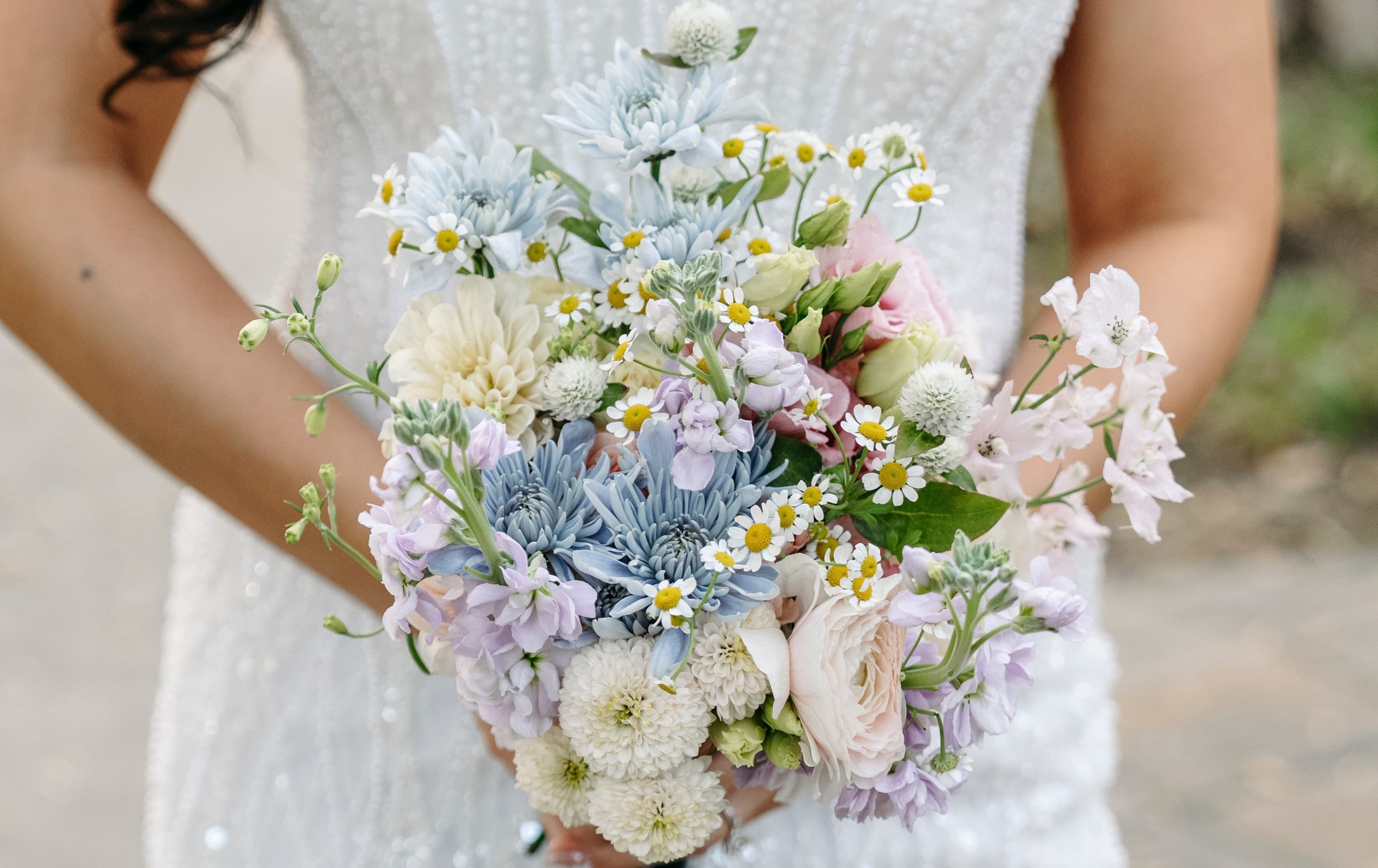 Bride holding a pastel bridal bouquet of blue, lavender and cream blooms